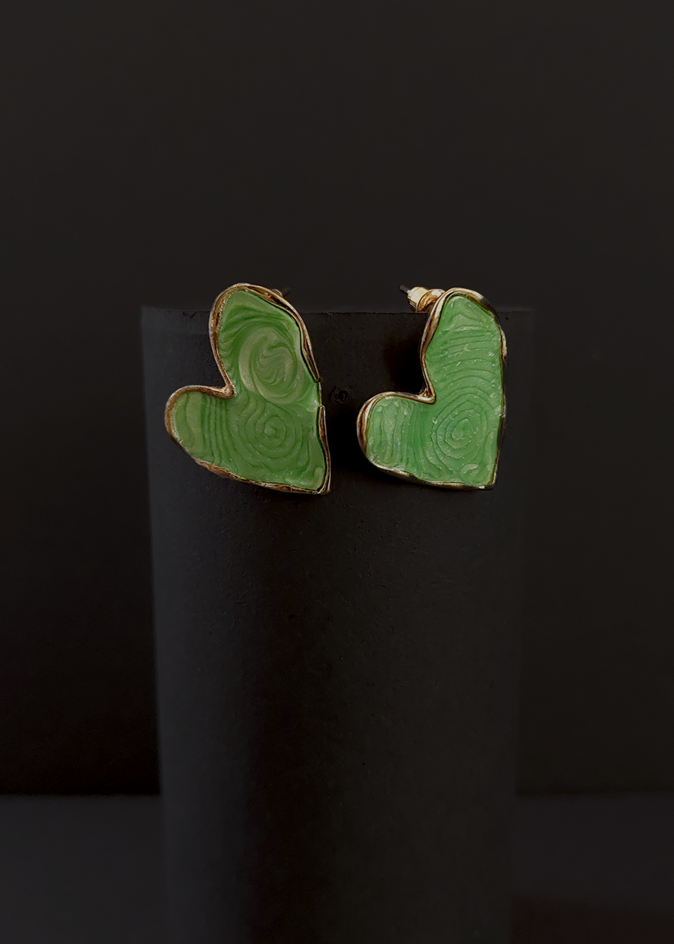 Green heart-shaped earrings on a black background