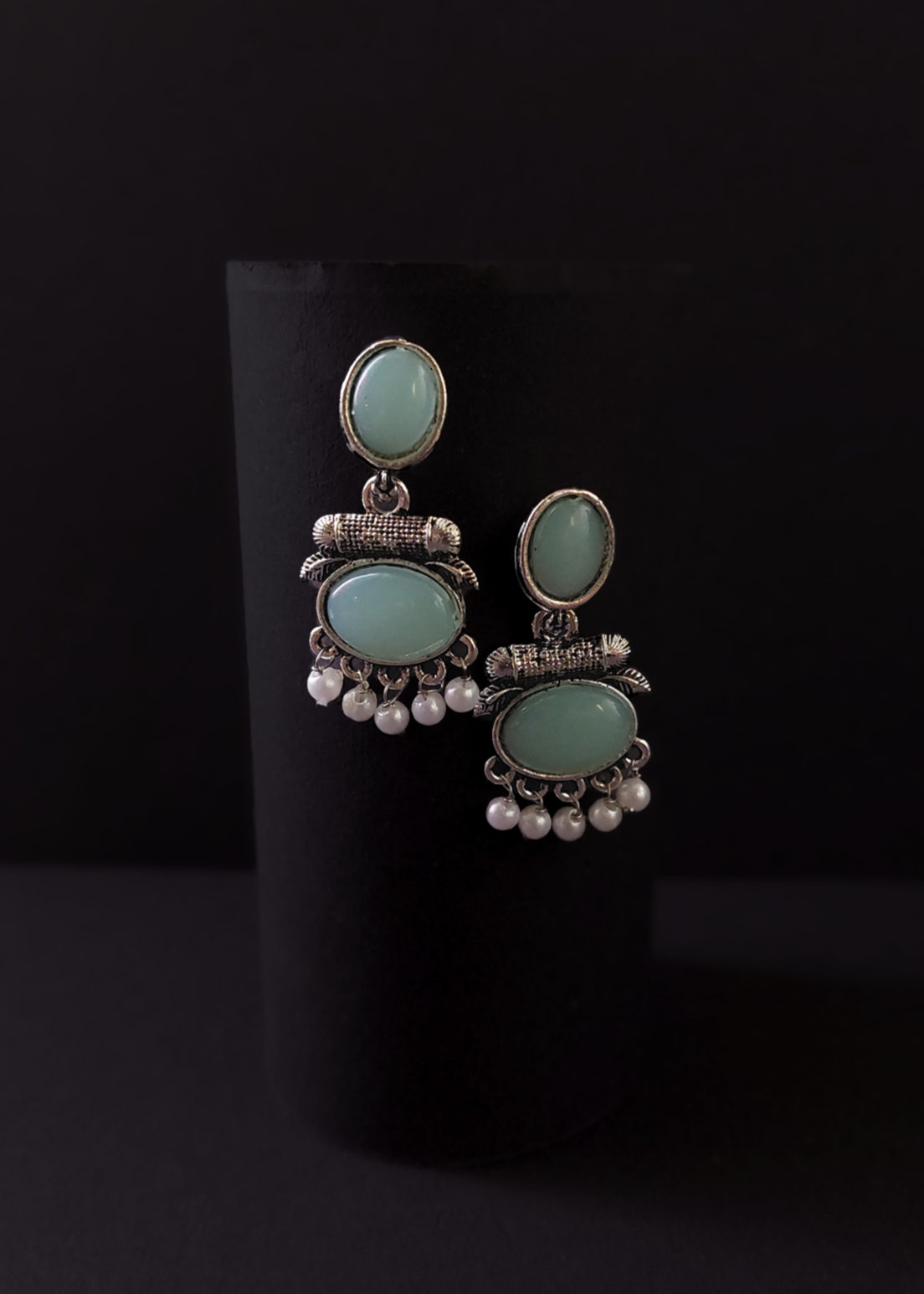 Pair of earrings with turquoise stones and silver accents on a black background