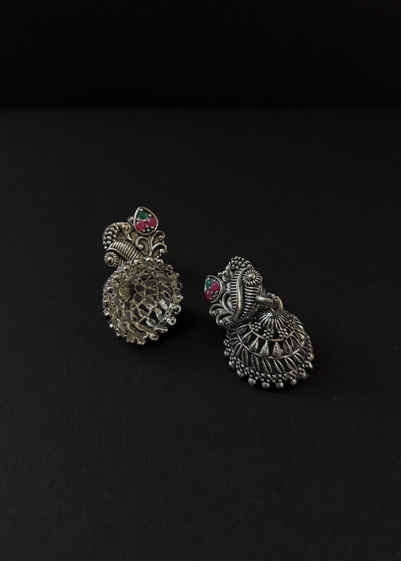Pair of silver earrings with red gemstones on a black background