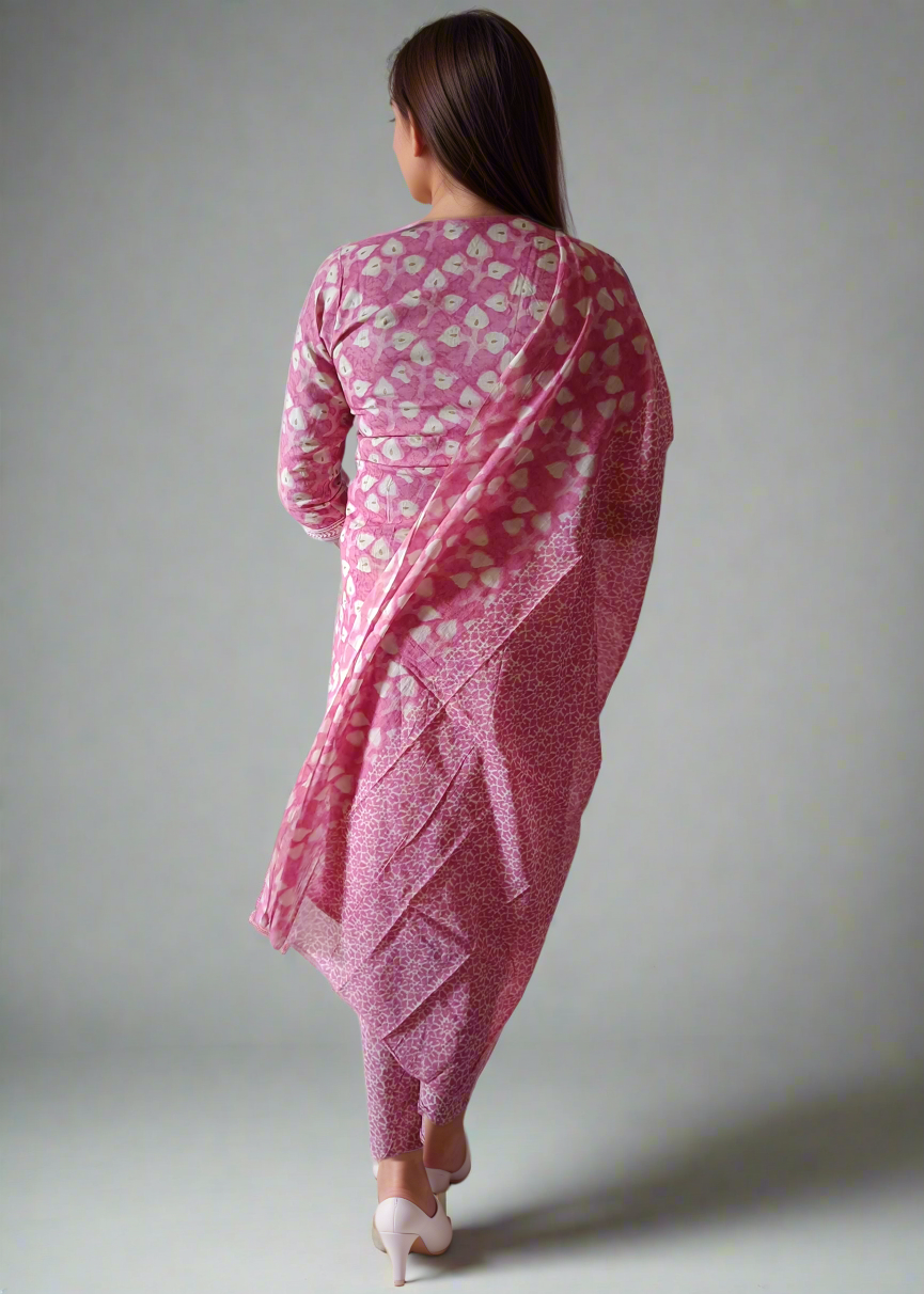 Woman wearing a pink floral silk salwar suit kurta set against a plain background