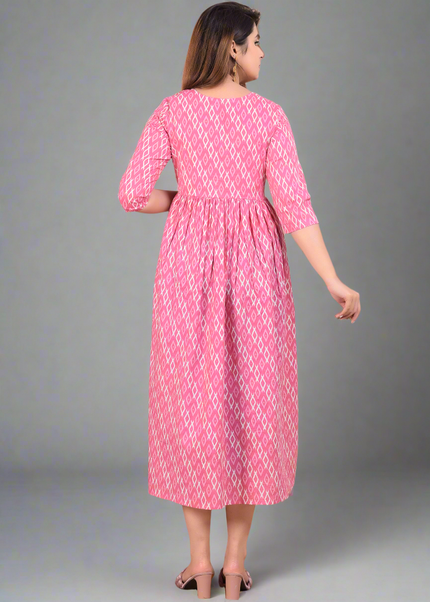Woman wearing a pink dress with white patterns, standing on a beige background.