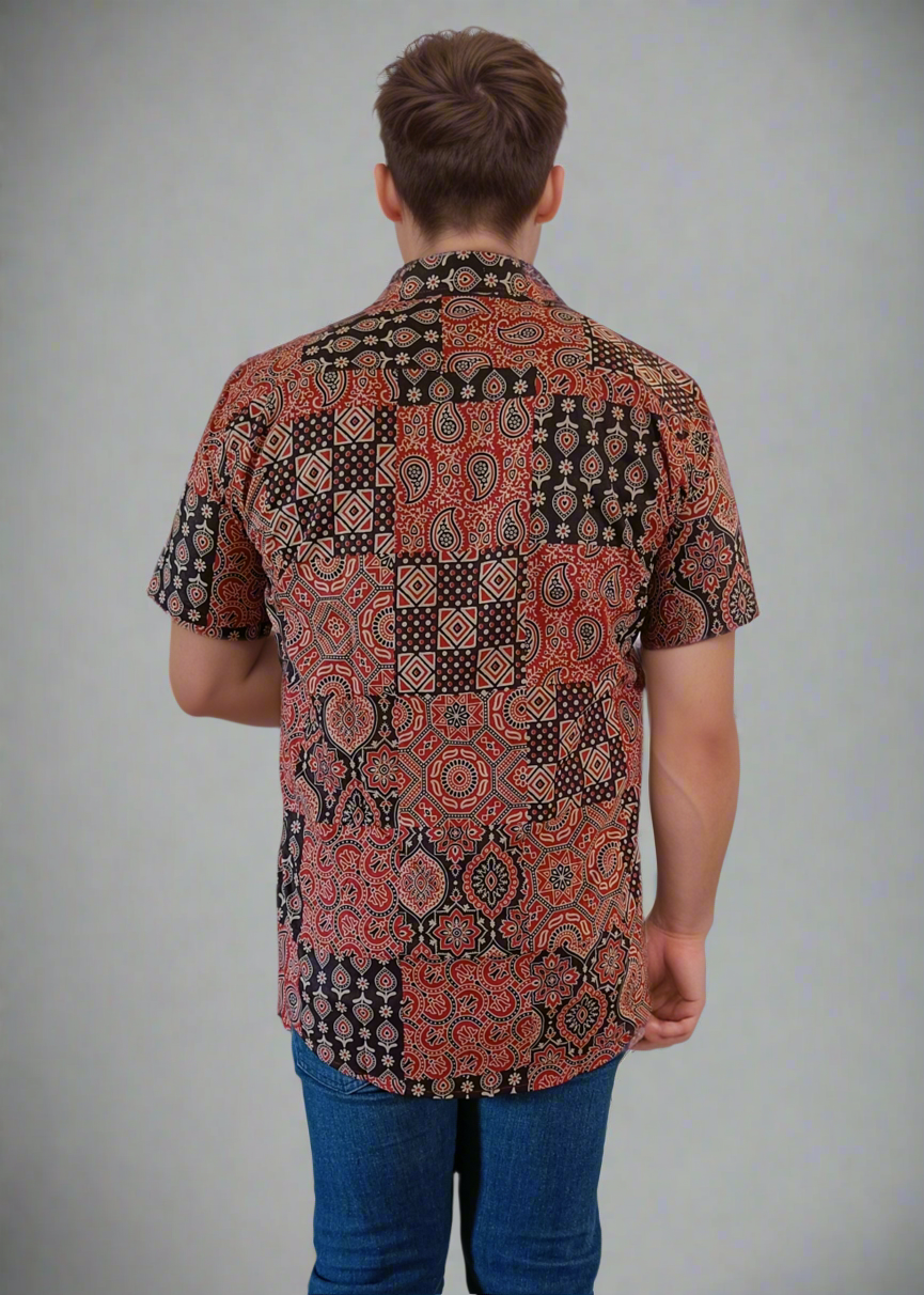 Person wearing a patterned shirt and blue jeans against a plain background