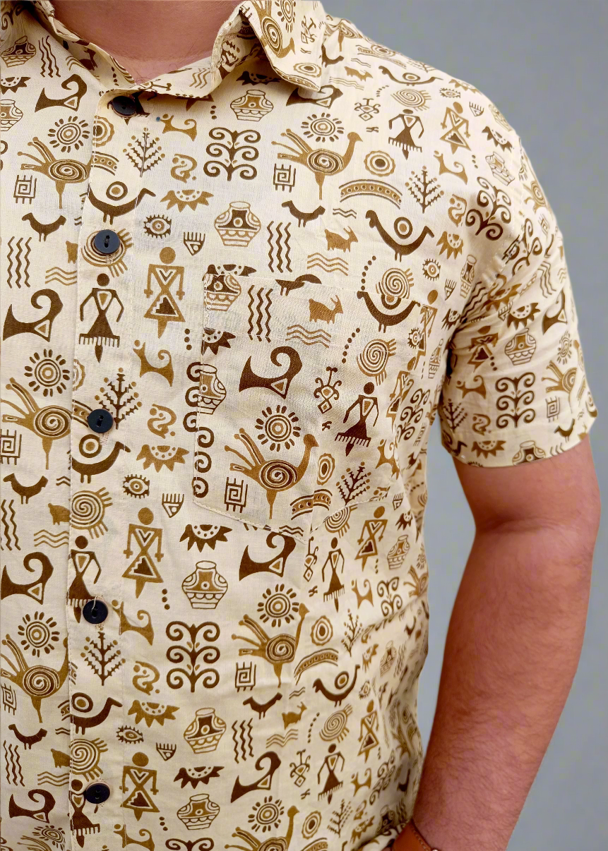 Close-up of a person wearing a patterned warli shirt with various symbols on a plain background