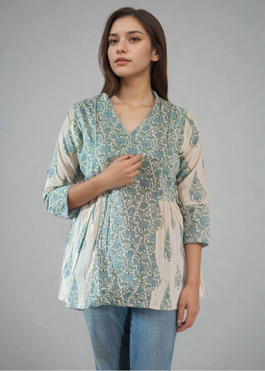 Woman wearing a patterned flroral paisley top and jeans on a plain background