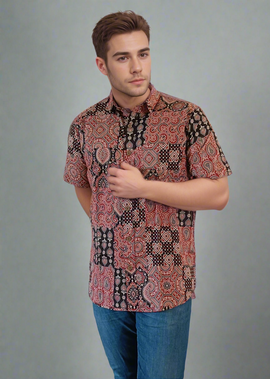Man wearing a patterned shirt and blue jeans on a plain background