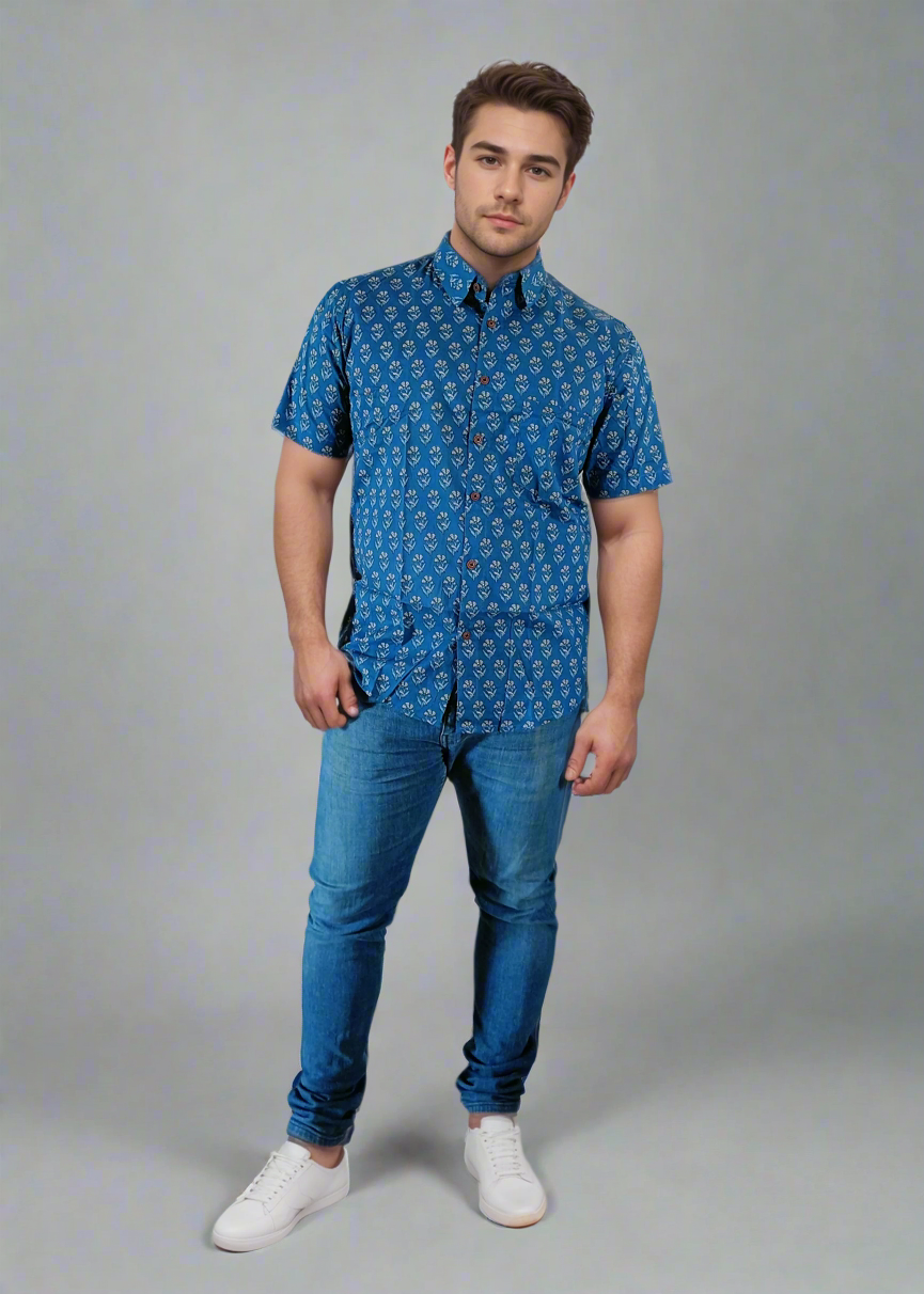 Man wearing a blue patterned shirt and jeans against a white background