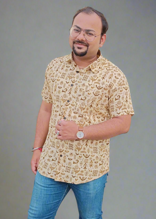 Man wearing a patterned beige shirt and blue jeans against a gray background