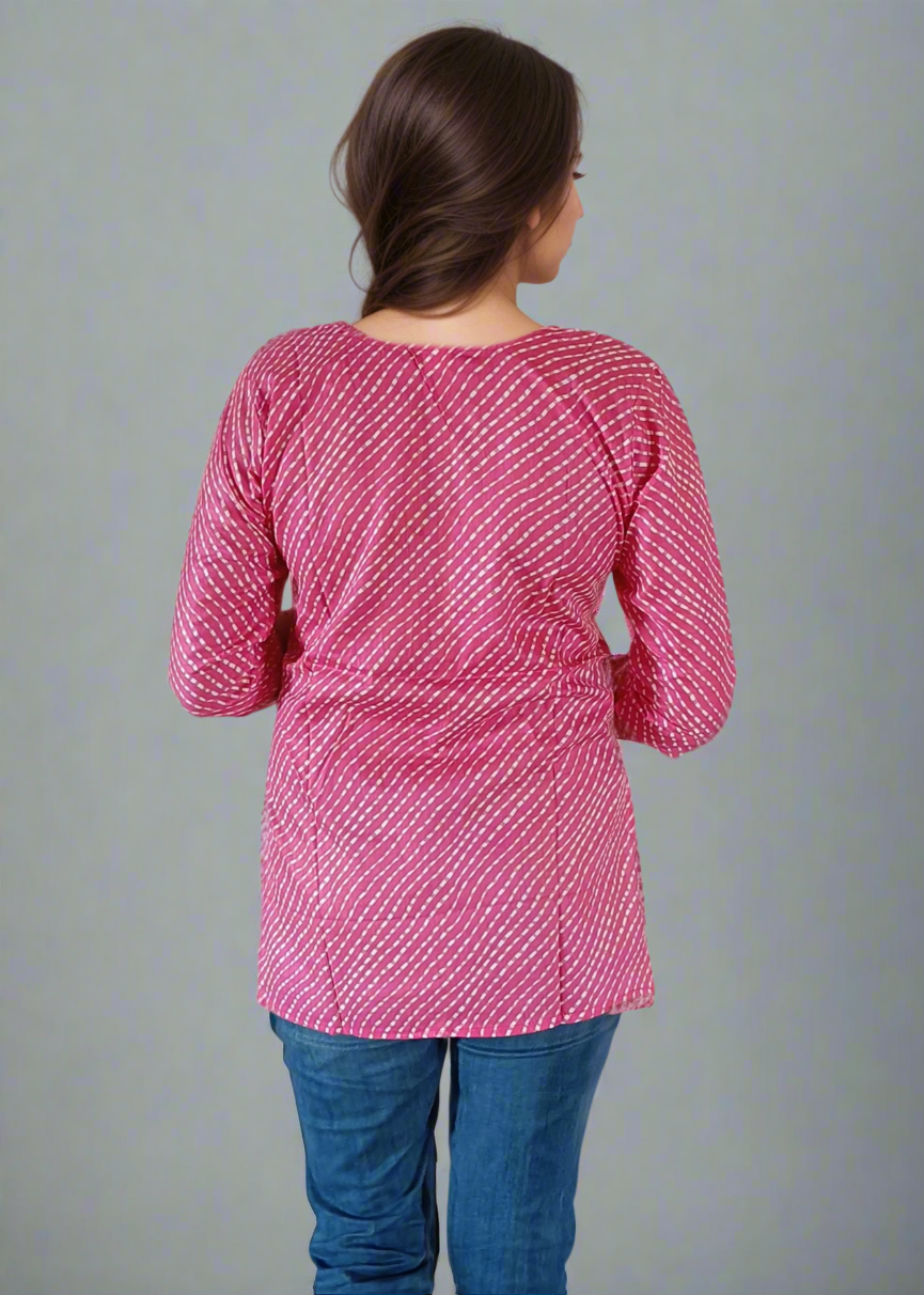 Person wearing a pink patterned top and blue jeans on a plain background