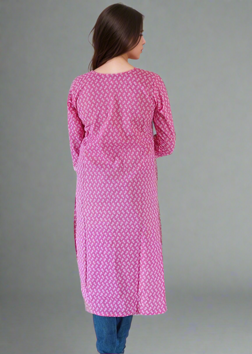 Woman wearing a pink patterned kurta with blue pants on a plain background
