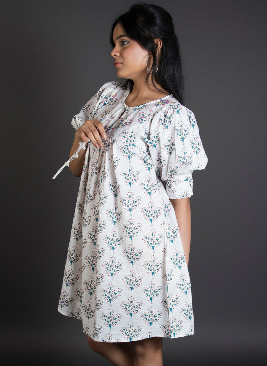 Woman in a floral knee length dress with puffed sleeve detail.