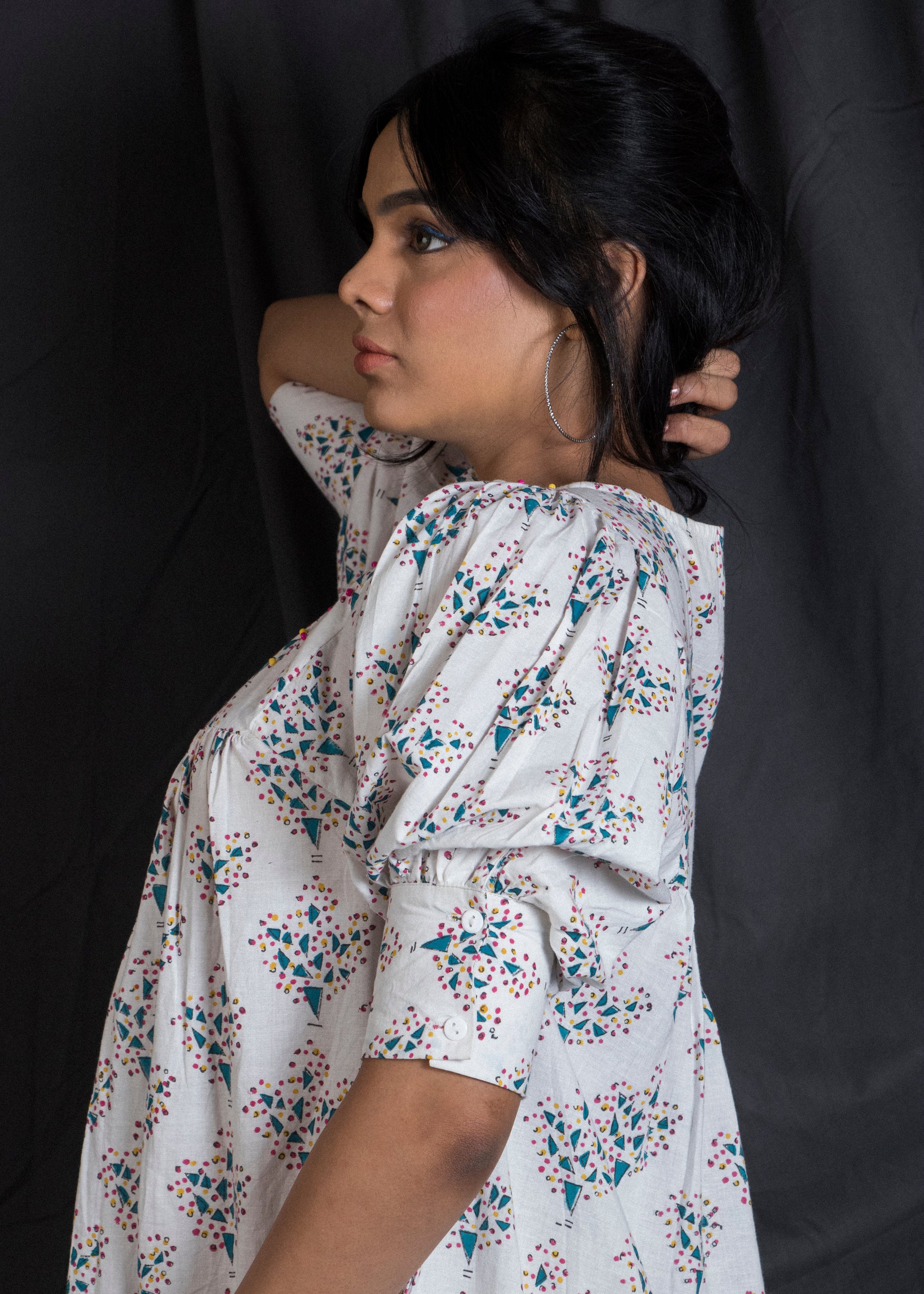 Woman wearing a white floral dress showcasing the puffed sleeve detail and cuff