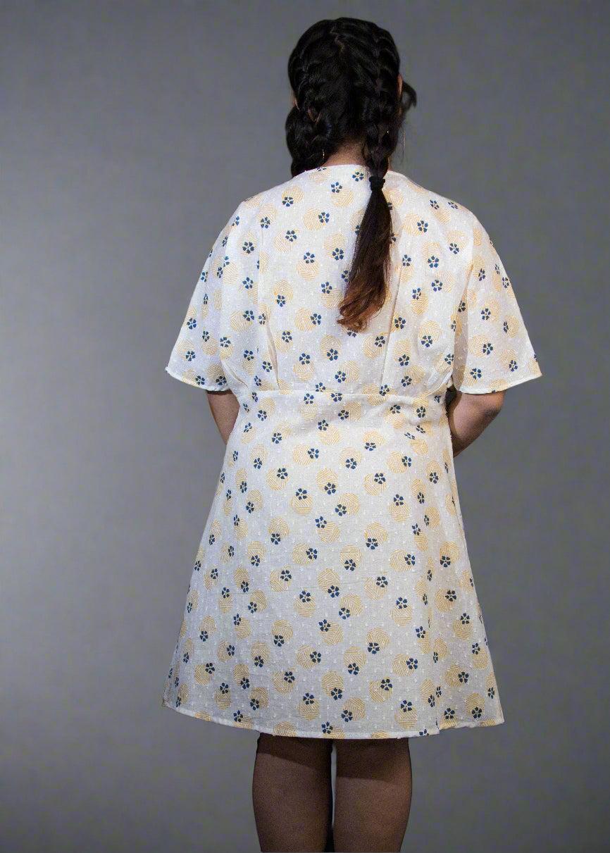 Person wearing a white dress with a floral pattern in a dark setting