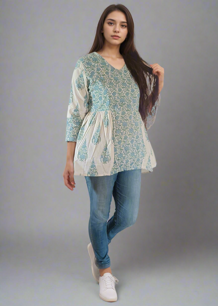 Woman wearing a floral flared tunic top and blue jeans against a plain background