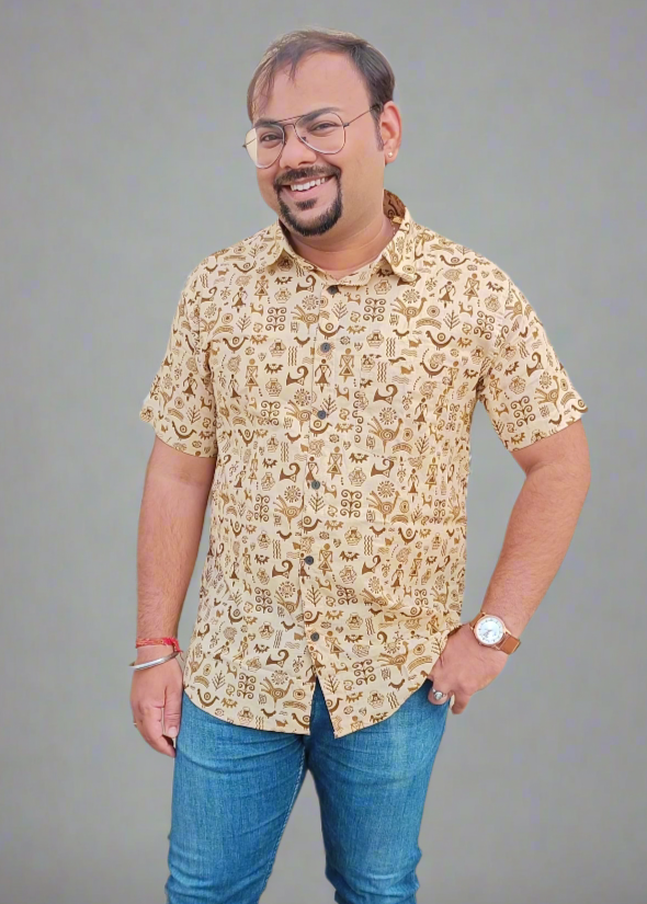 Man wearing a patterned beige shirt and blue jeans against a gray background