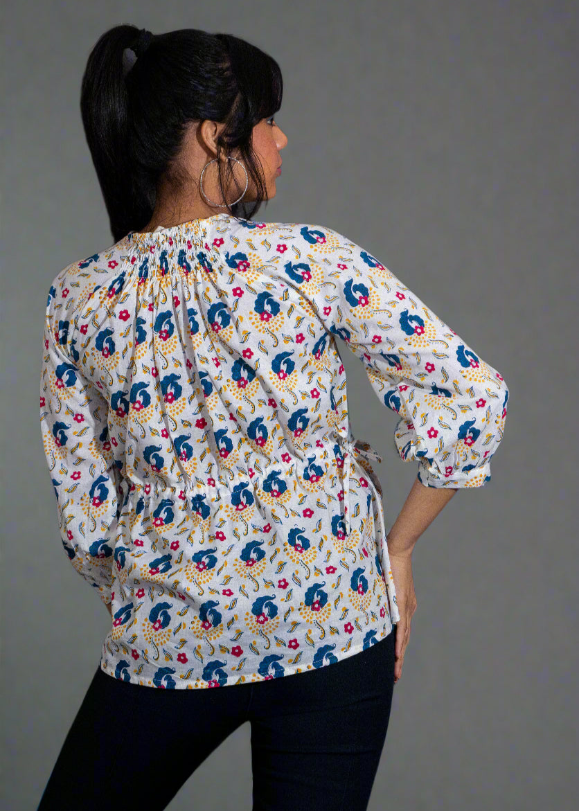 Woman wearing a hand block floral paisley blouse against a dark background