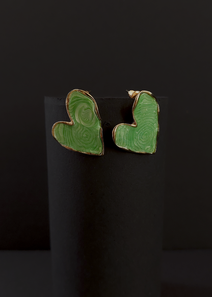Green heart-shaped earrings on a black background
