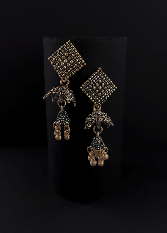 Pair of ornate gold earrings on a black background