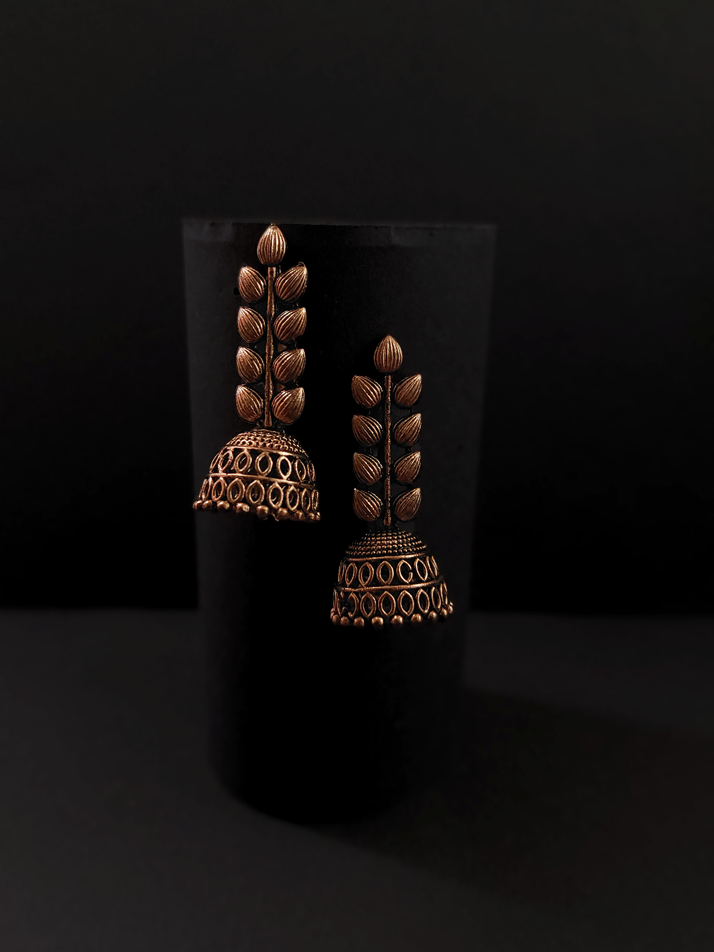 Pair of ornate bronze earrings on a black background