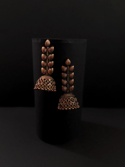Pair of ornate bronze earrings on a black background