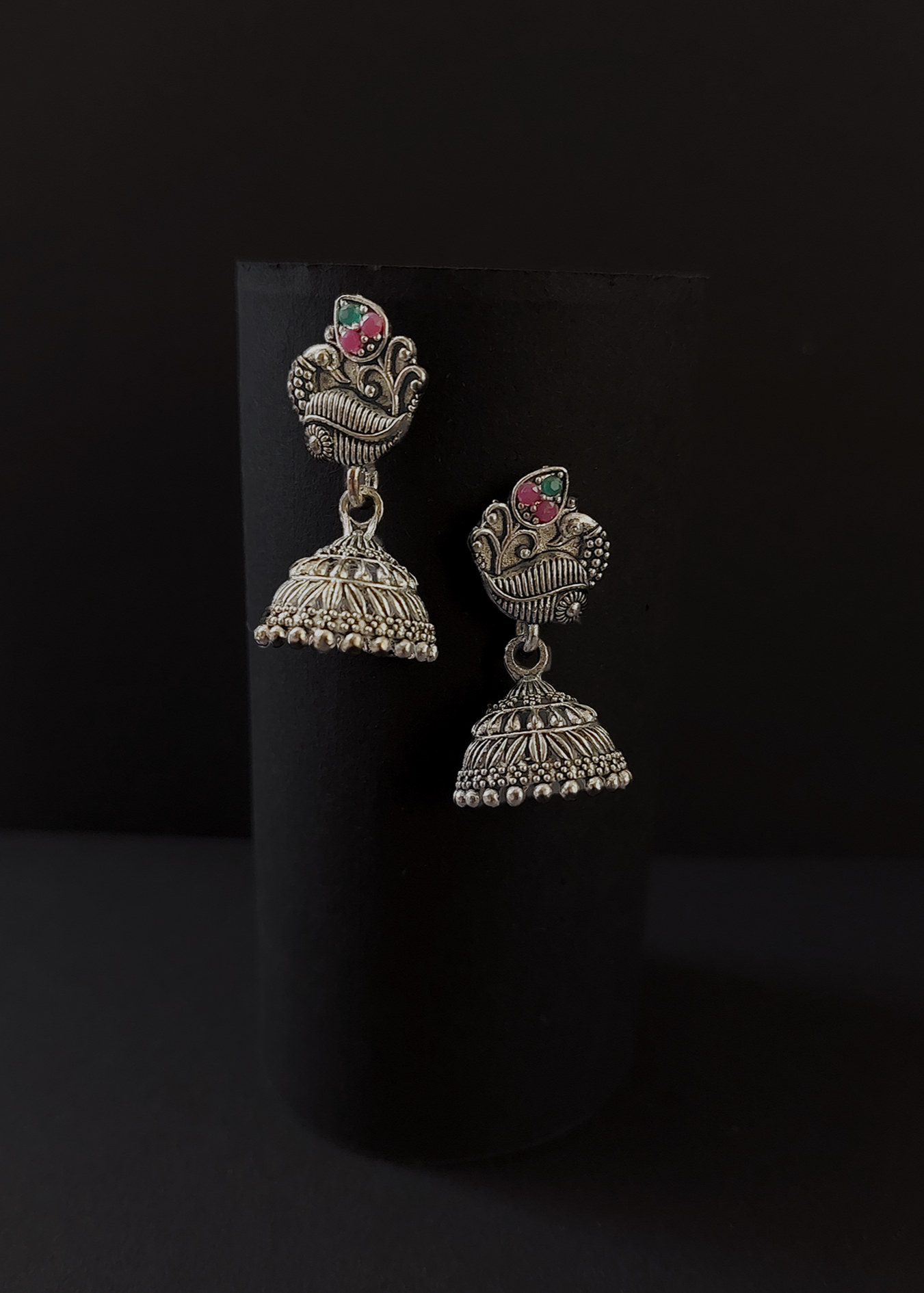 Pair of silver jhumka earrings on a black background