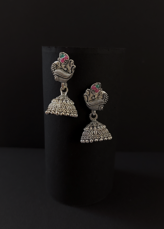 Pair of silver jhumka earrings on a black background