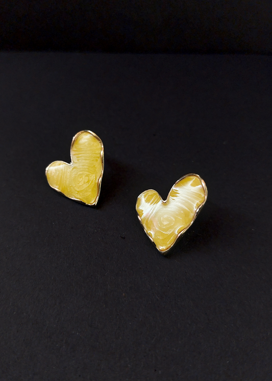 Heart-shaped gold earrings on a black background