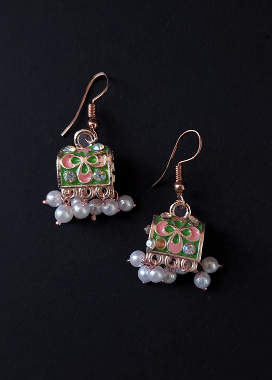 Pair of earrings with floral design and pearl accents on a black background