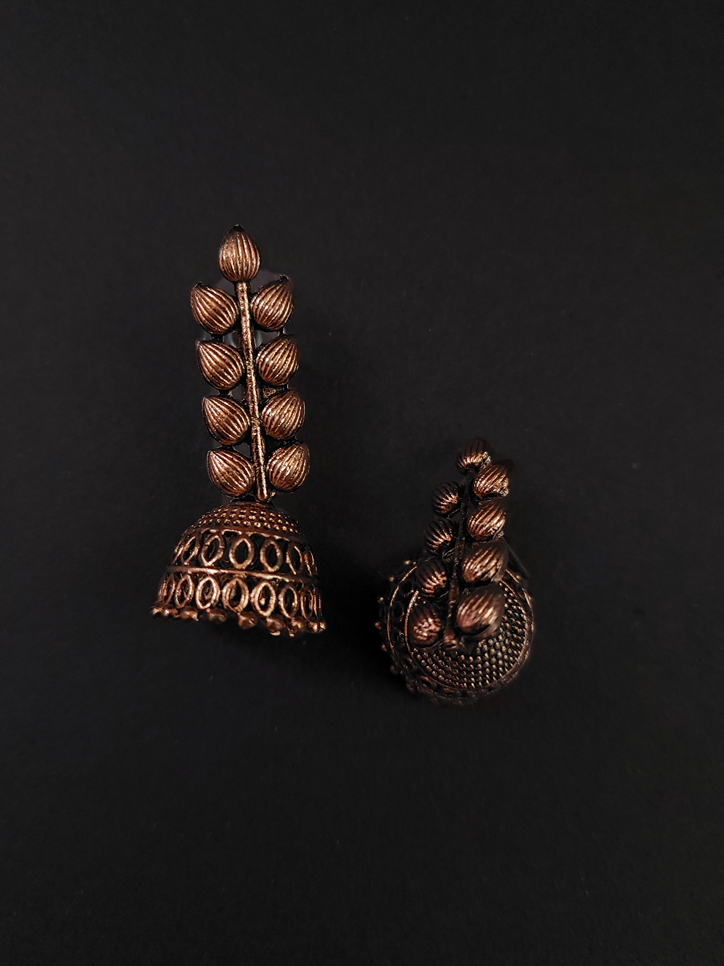 Pair of ornate bronze earrings on a black background