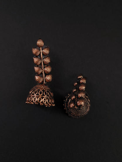 Pair of ornate bronze earrings on a black background