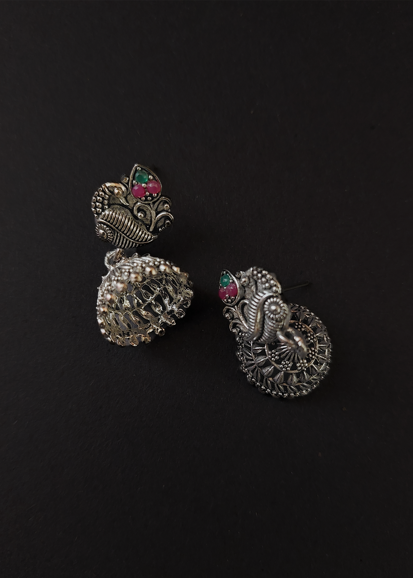 Pair of silver earrings with gemstones on a black background