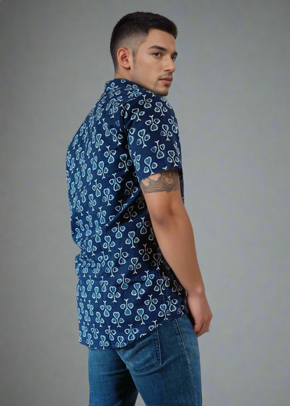Man wearing a blue patterned shirt and jeans on a white background