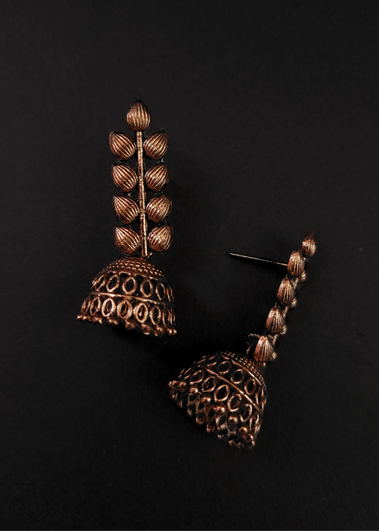 Pair of ornate copper earrings on a black background