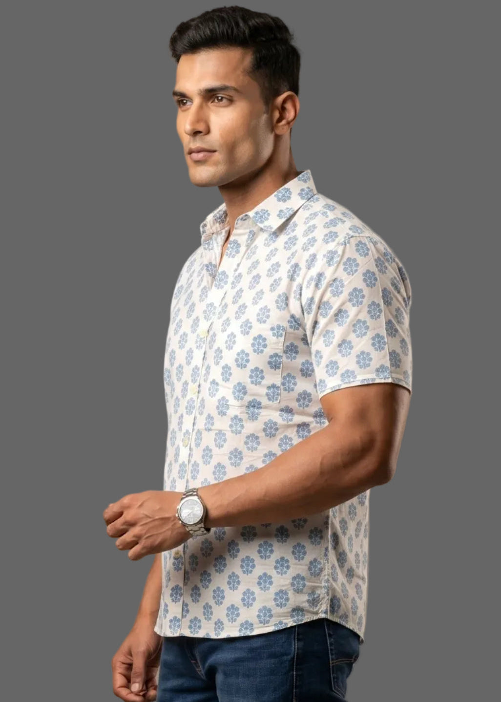 Man wearing a patterned half sleeve cotton shirt and dark jeans on a brown background