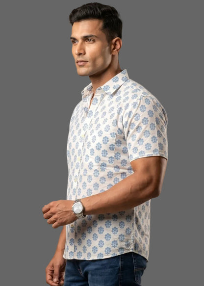 Man wearing a patterned half sleeve cotton shirt and dark jeans on a brown background