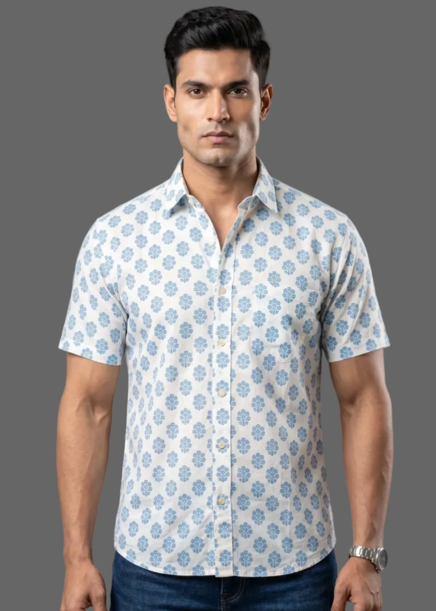 Man wearing a patterned half sleeve cotton shirt and jeans against a gray background