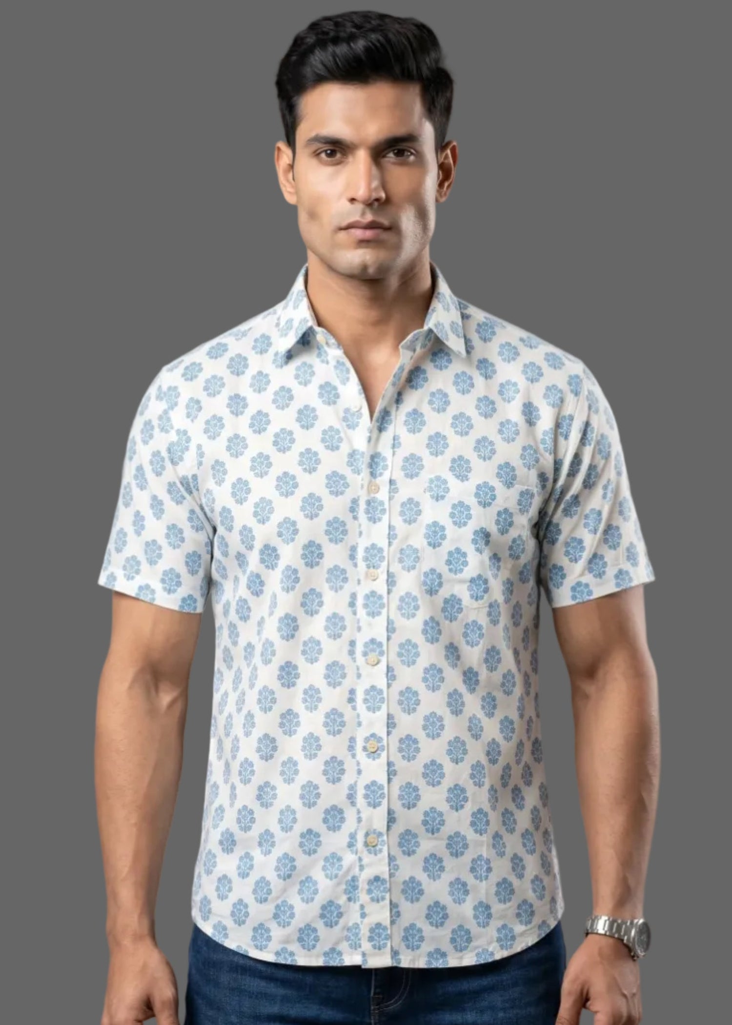 Man wearing a patterned half sleeve cotton shirt and jeans against a gray background