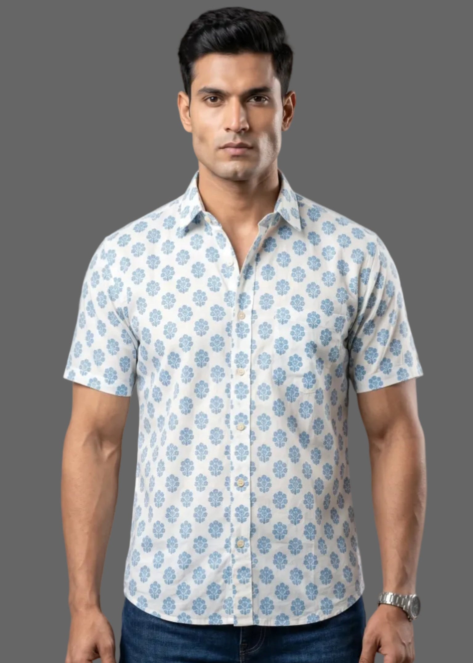 Man wearing a patterned half sleeve cotton shirt and jeans against a gray background