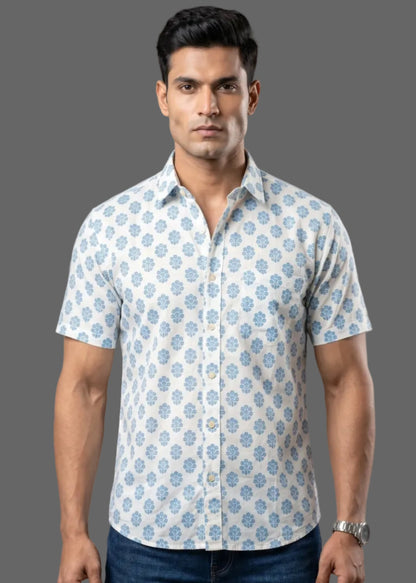 Man wearing a patterned half sleeve cotton shirt and jeans against a gray background