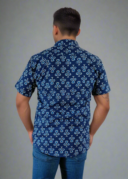 Man wearing a blue patterned shirt and jeans against a white background