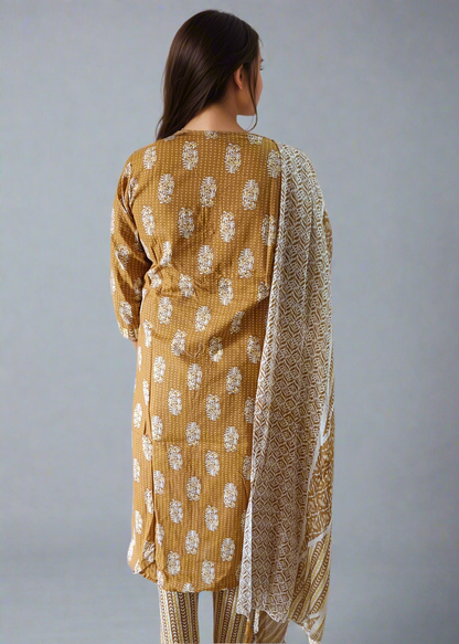 Woman wearing a mustard yellow patterned outfit with a matching dupatta on a plain background