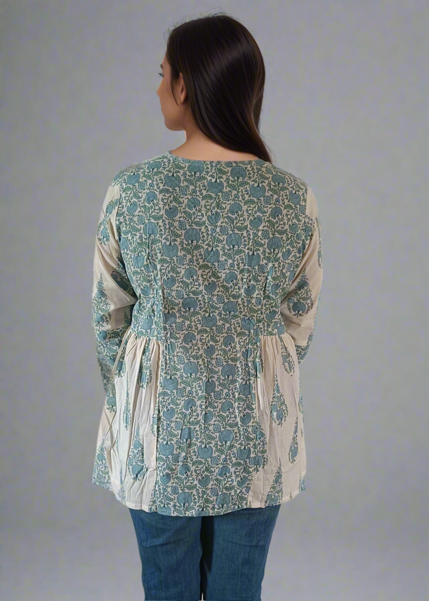Woman wearing a patterned flroral paisley top and jeans on a plain background