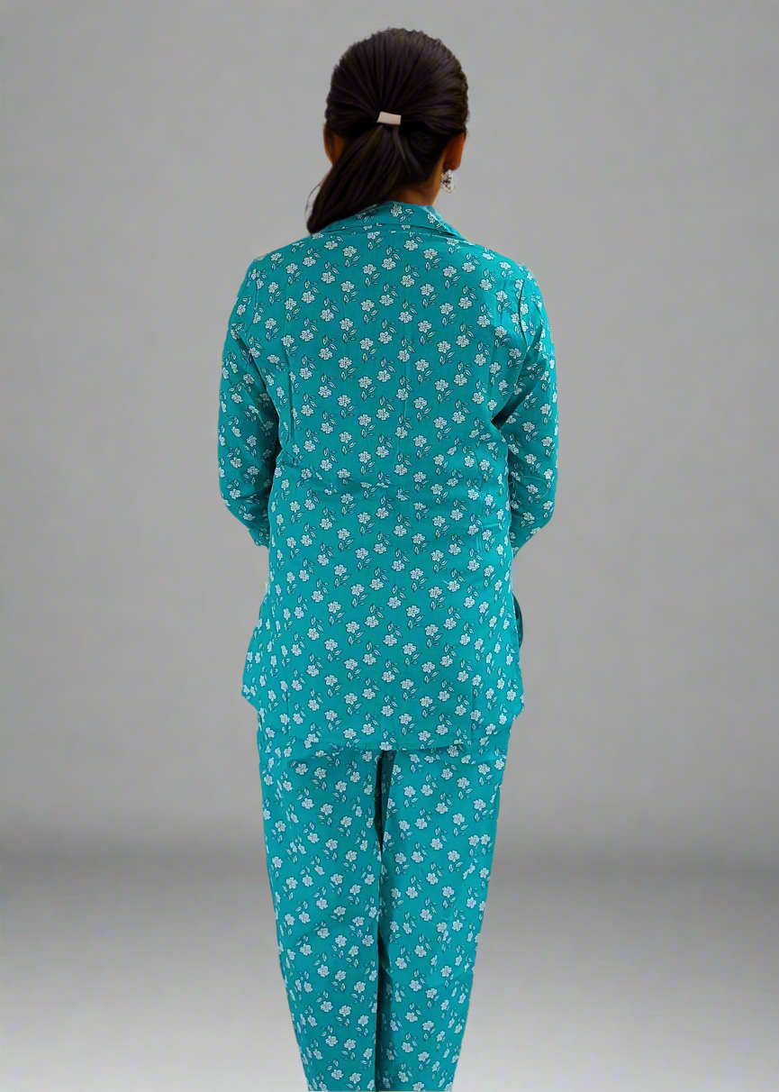 Person wearing a teal pajama set with a white floral pattern on a plain background