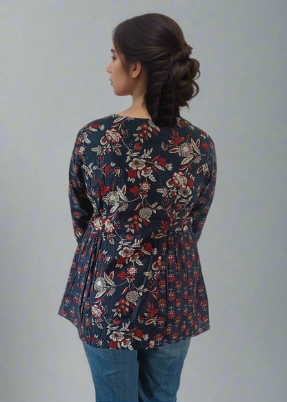 Woman wearing a floral top and blue jeans on a plain background