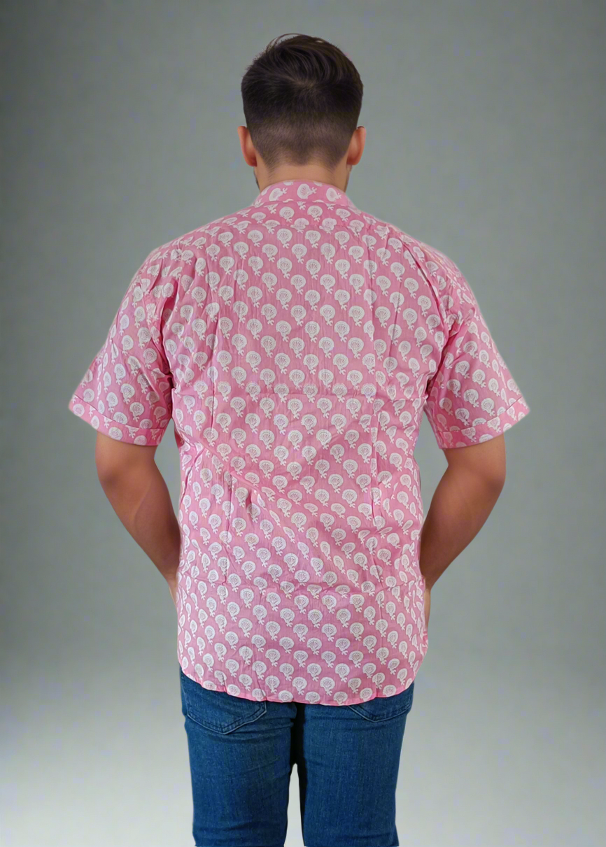 Person wearing a pink patterned shirt and blue jeans against a plain background