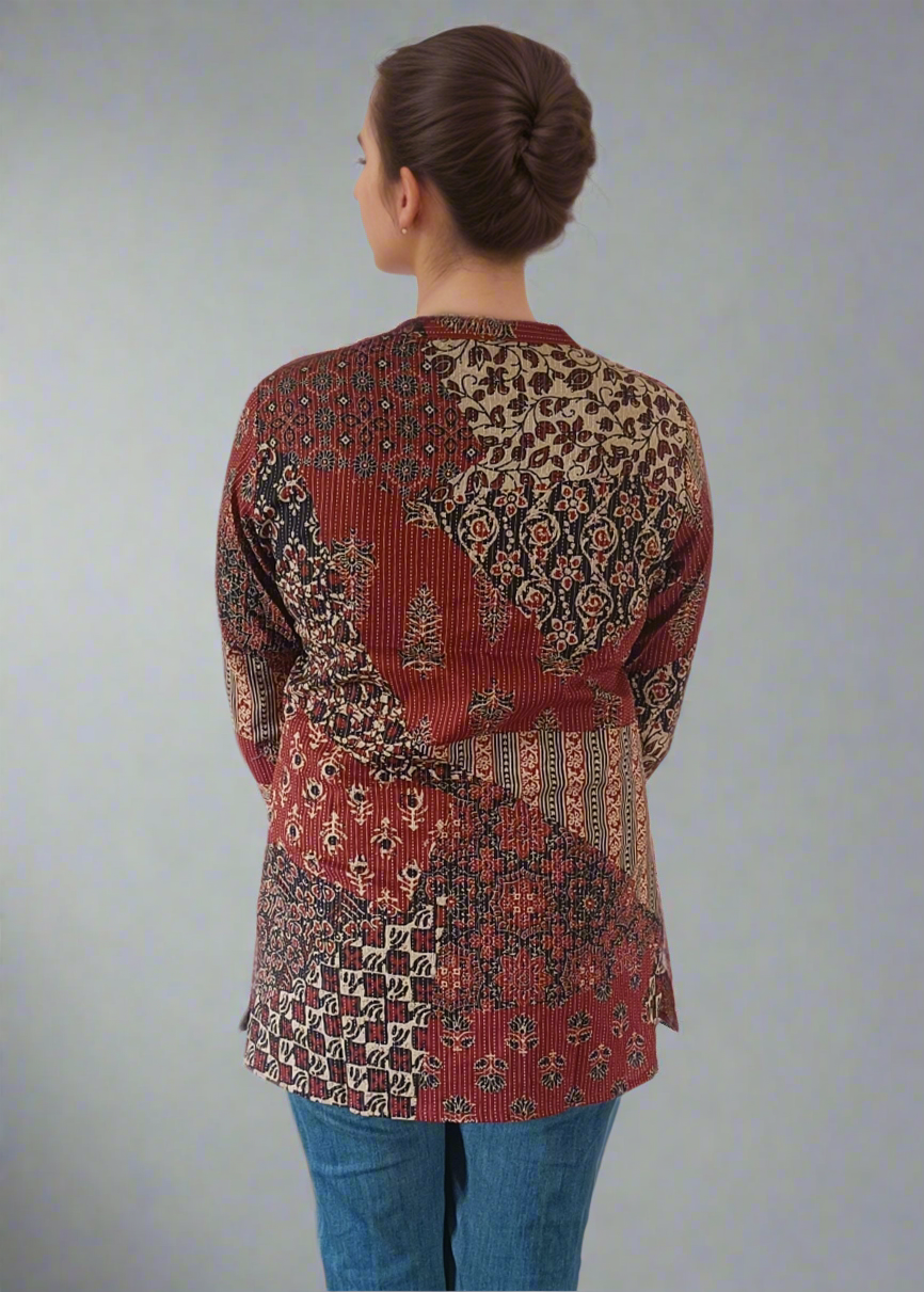 Person wearing a patterned top and blue jeans on a plain background