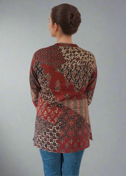 Person wearing a patterned top and blue jeans on a plain background