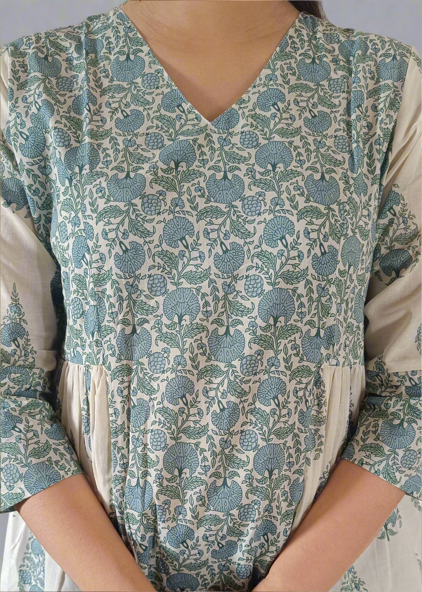 Woman wearing a patterned flroral paisley top and jeans on a plain background