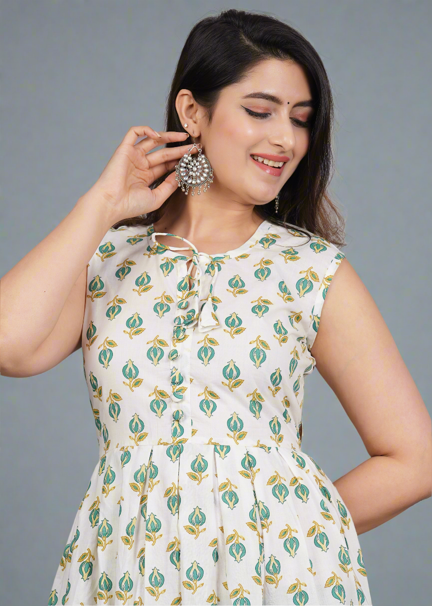 Woman wearing a white dress with green floral pattern against a gray background