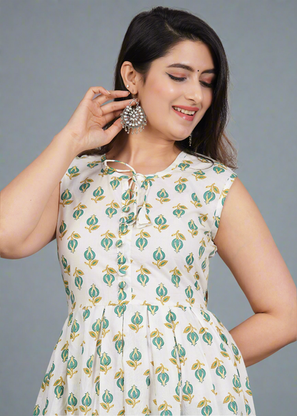 Woman wearing a white dress with green floral pattern against a gray background