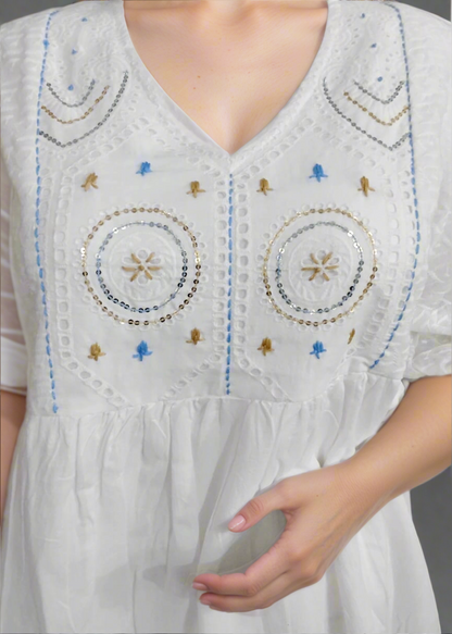 White dress with intricate beadwork on a plain background
